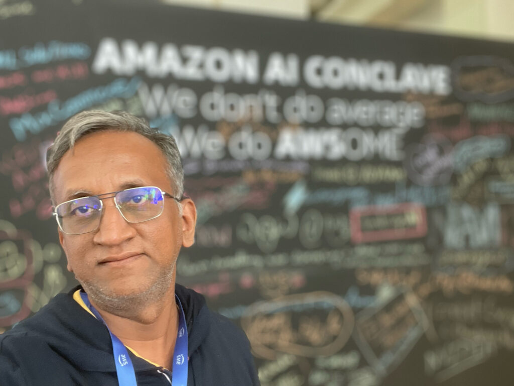 Participant at an Amazon AI Conclave taking a selfie in front of a chalkboard filled with AI concepts and notes.